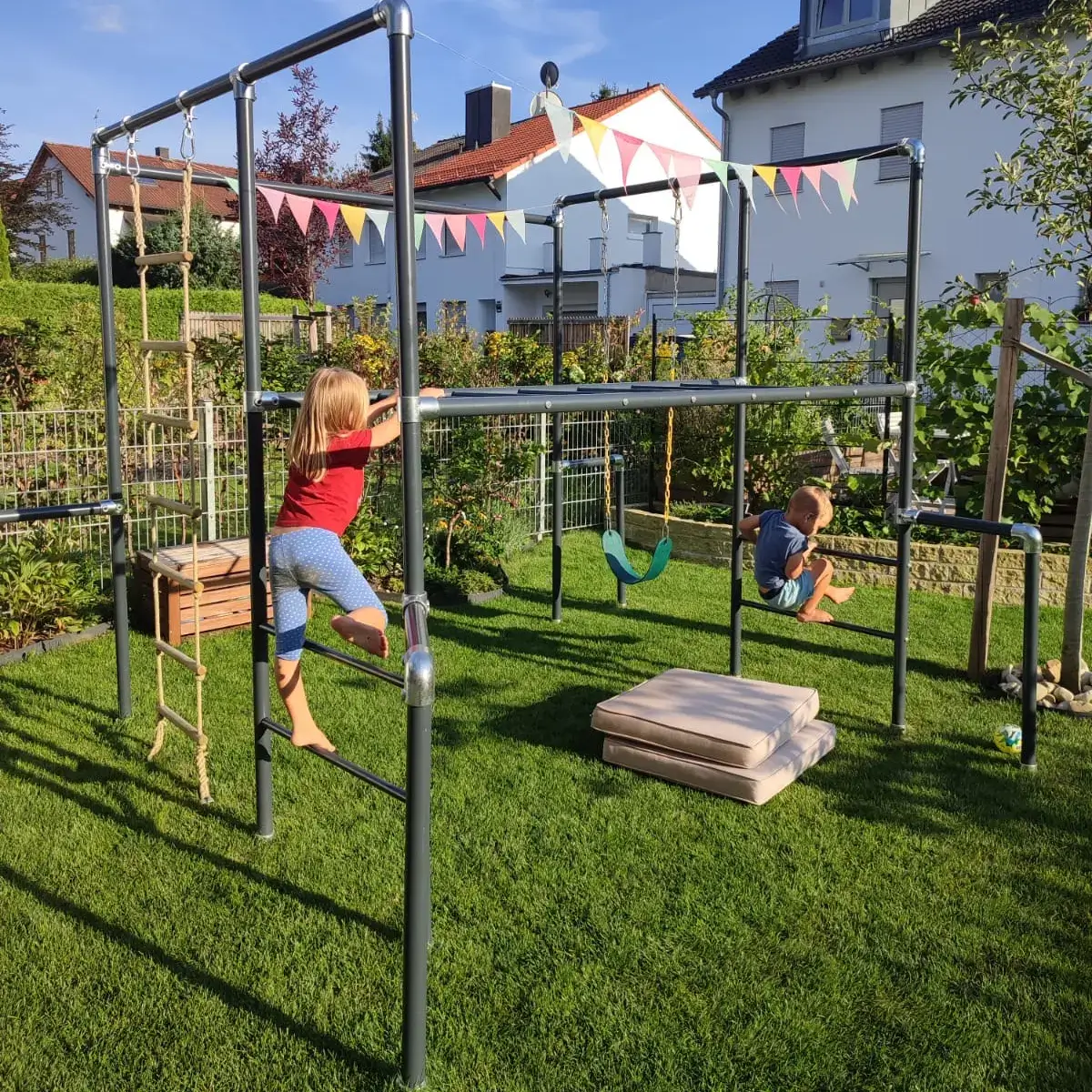 Zwei Kinder spielen an einem FOURACTION-Klettergerüst im Garten