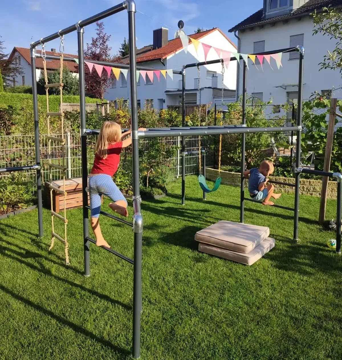 Mädchen klettert an einem Gerüst, über dem eine bunte Wimpelkette hängt