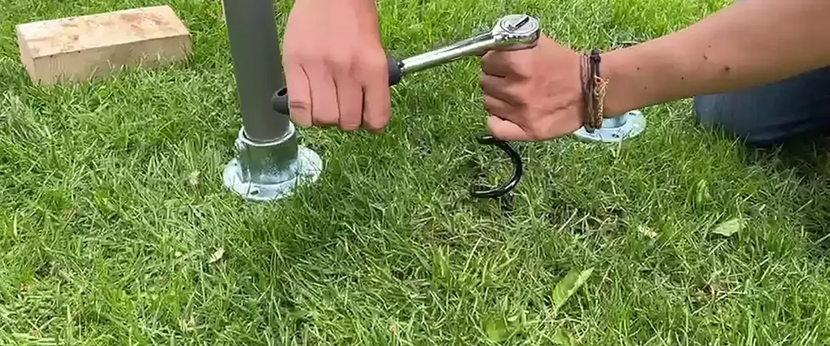Zwei Hände drehen mit einer Ratsche einen Spiralhering neben der Bodenplatte ein