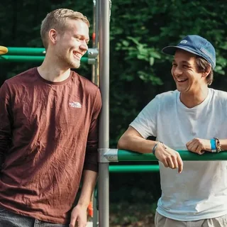 Simon und Simon von FOURACTION lachen an einem grünen Klettergerüst