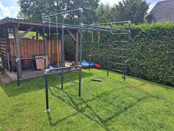 Klettergerüst mit Schaukeln vor dem Holzunterstand im Garten von Kim Bonz