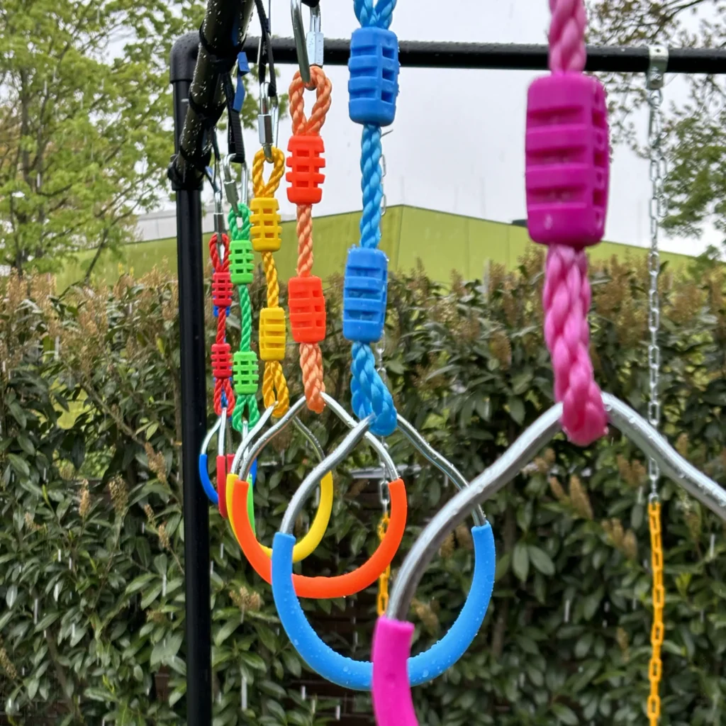 Bunte FOURACTION Turnringe aufgehängt an schwarzem Klettergerüst