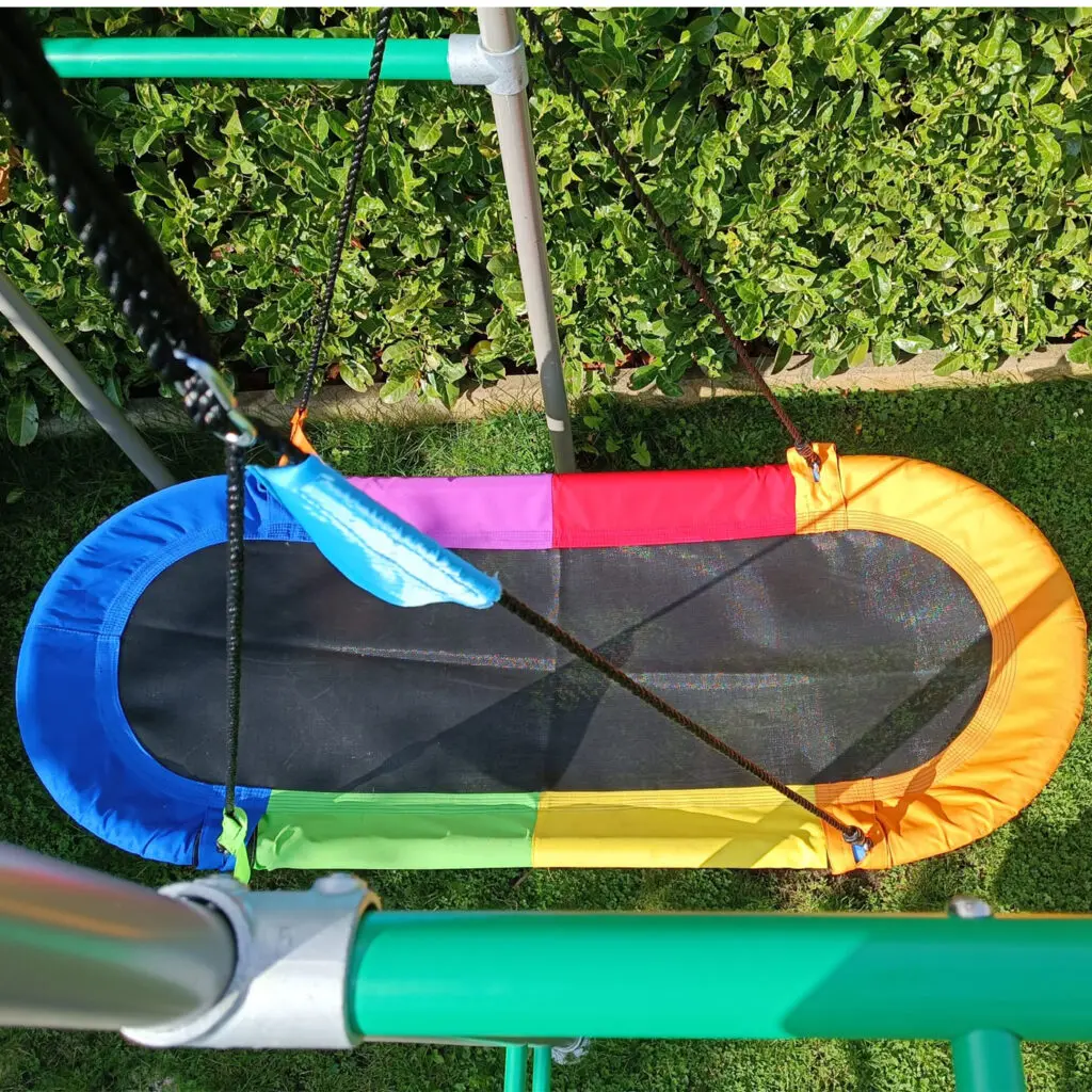 Oval Swing Nestschaukel Nahaufnahme vor grüner Hecke im Garten