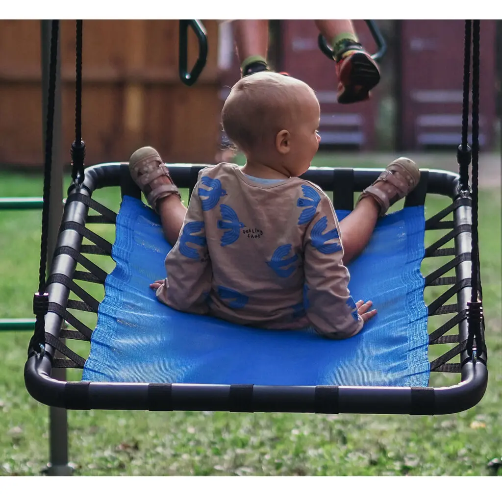 Kleinkind sitzt auf der Platform Swing Plattformschaukel im Garten