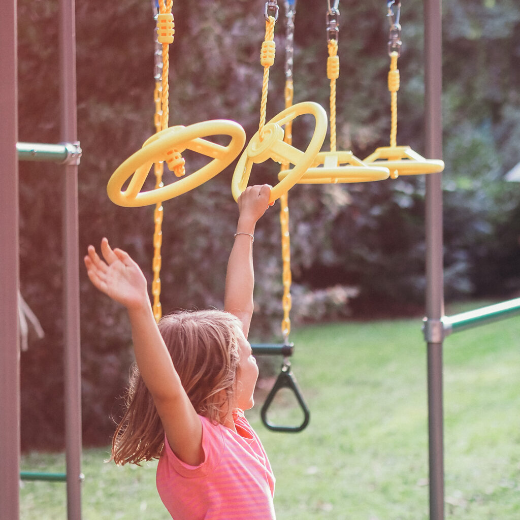 Kind spielt an Ninja Wheels Hangelrädern im Outdoor Ninja-Parcours