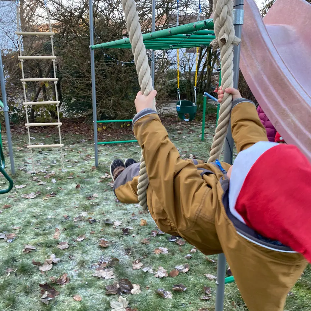 Kind schaukelt am 2 Meter Kletterseil im Klettergerüst