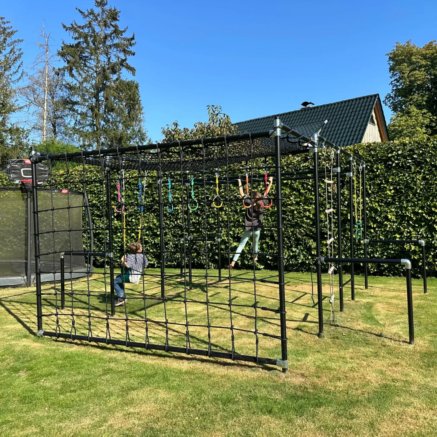 Kinder klettern auf einem großen FOURACTION Klettergerüst aus Metall im Garten